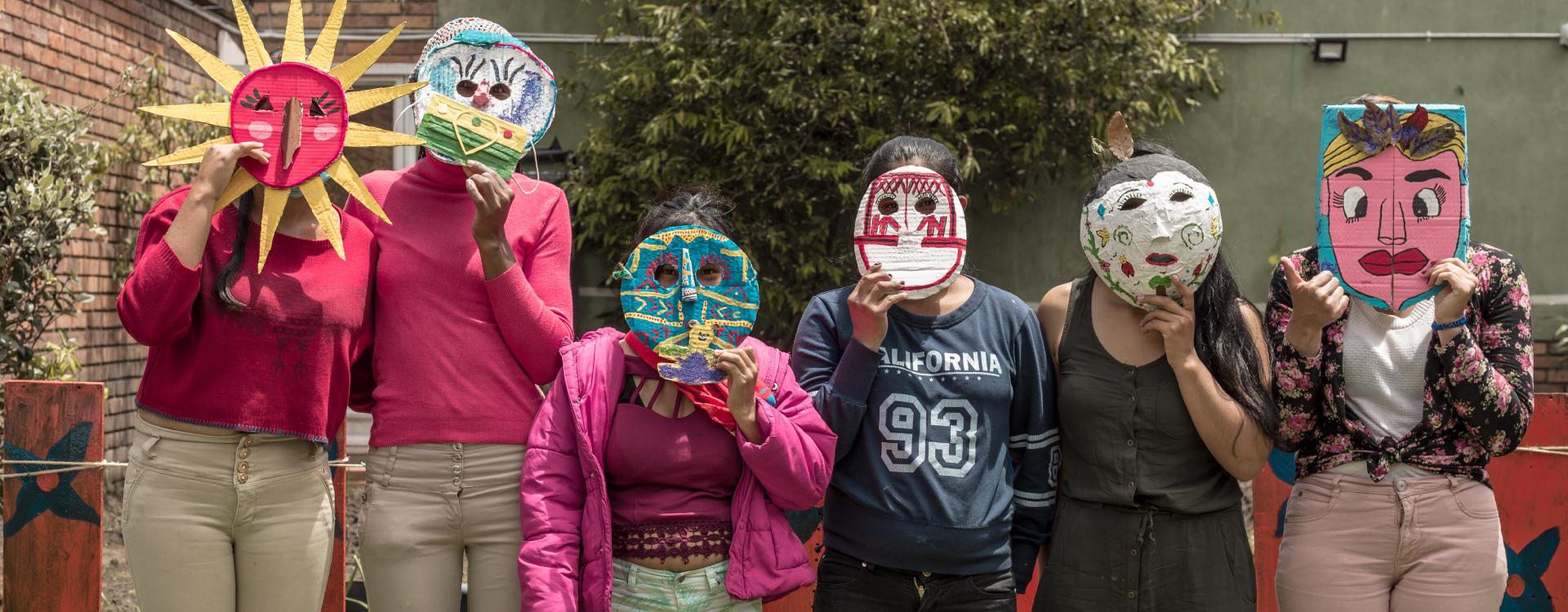 Mujeres con mascaras de cartón ocultan sus rostros