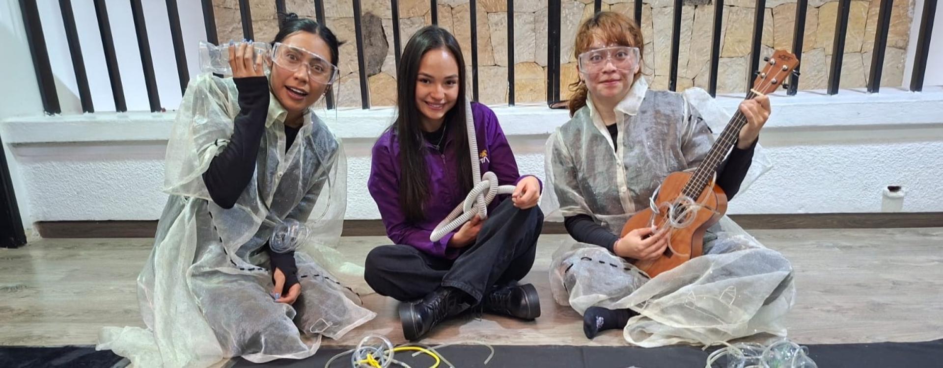 Mujeres sentadas en un andén sonrrientes con instrumentos en la mano