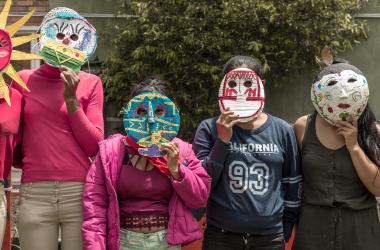 Mujeres con mascaras de cartón ocultan sus rostros