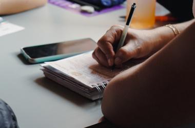 Manos de mujer mayor escribiendo en libreta